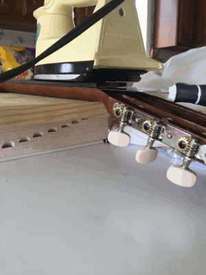 a paint scrapper removing a classical guitar fretboard